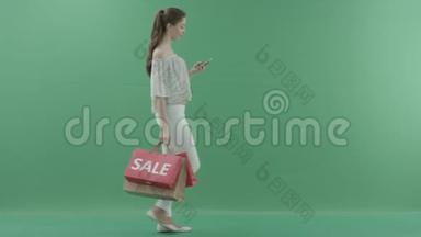 年轻有魅力的女人在智能手机上散步和<strong>上网</strong>，把袋子放在<strong>绿色</strong>屏幕上